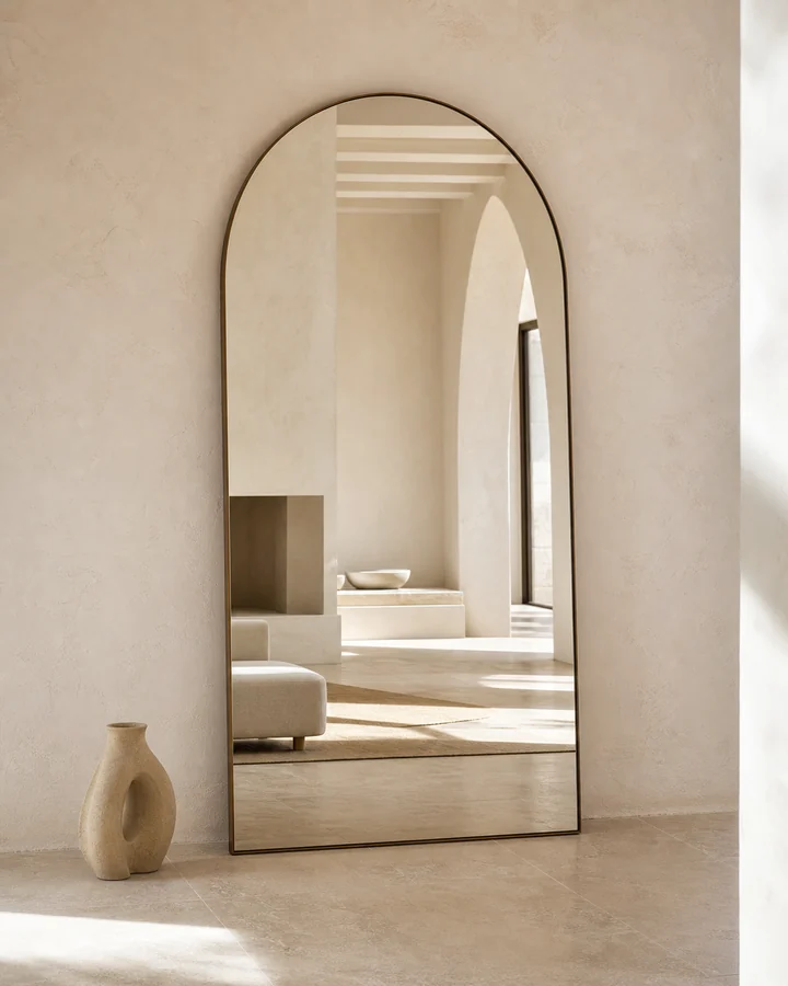 Miroir arqué à bord bronze dans un intérieur lumineux